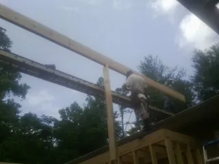 Carpenter setting a ridge beam over a new addition frame — Ice Dam Removal by Roofing Brothers in Diberville