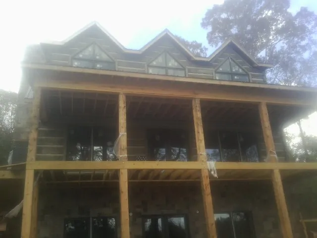 Dormers and porch framing on a large log home under construction — Roof Coating work by our crew in Diberville
