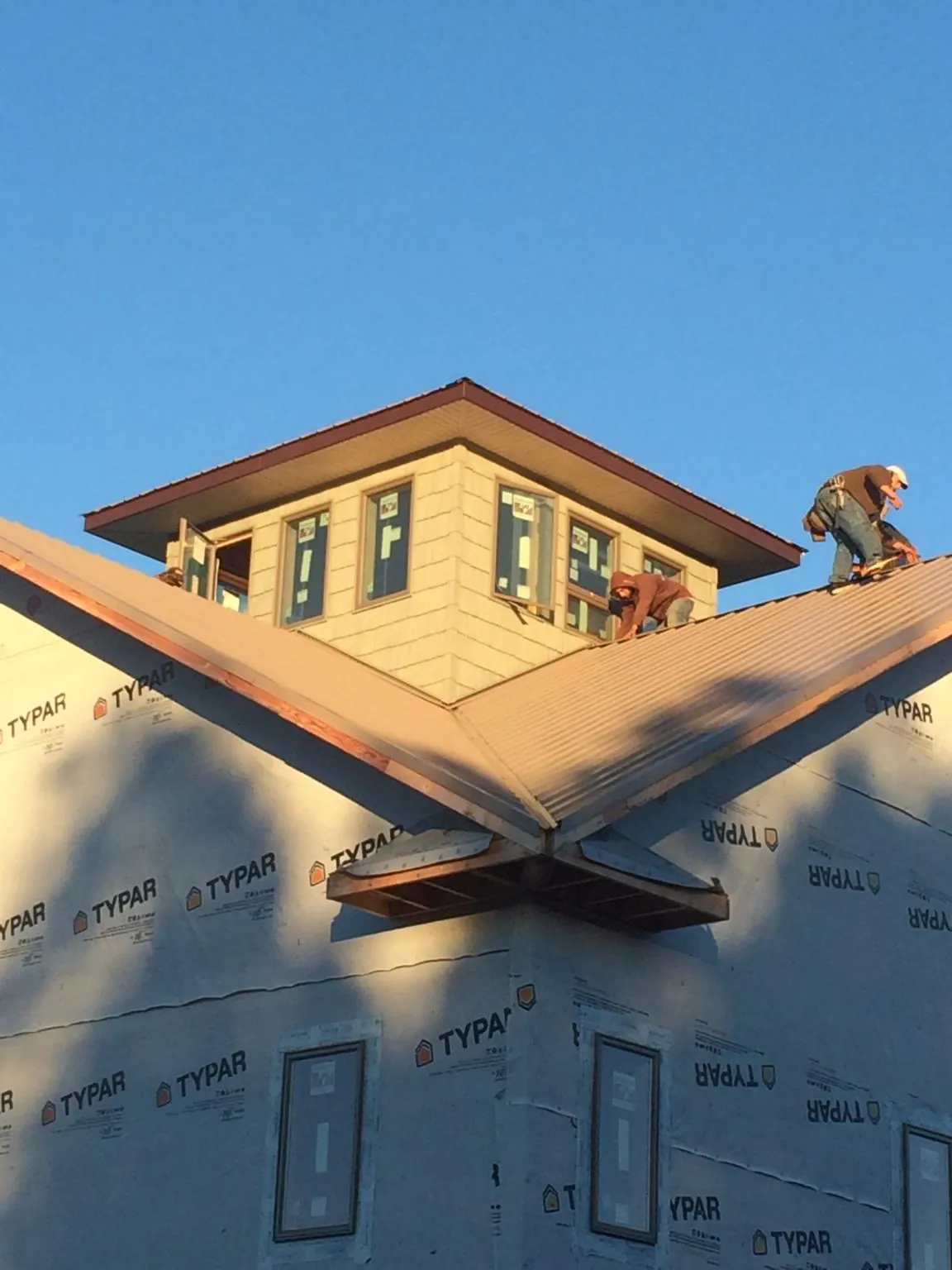 Roofers working around a rooftop cupola on a new metal roof at sunset — Roof Waterproofing in Diberville by Roofing Brothers